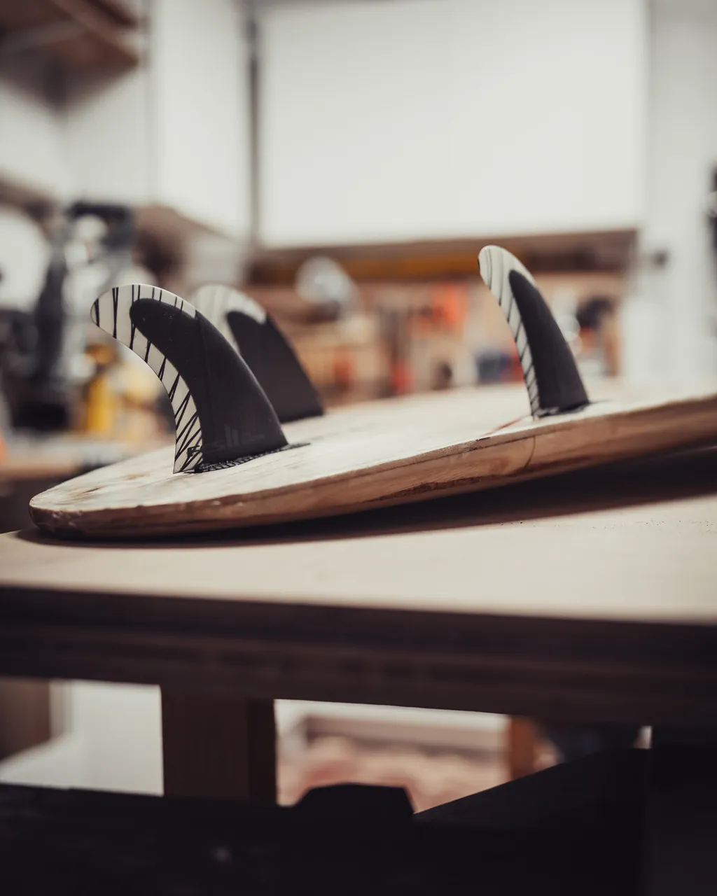 A finished board on the workbench with three fins fitted.