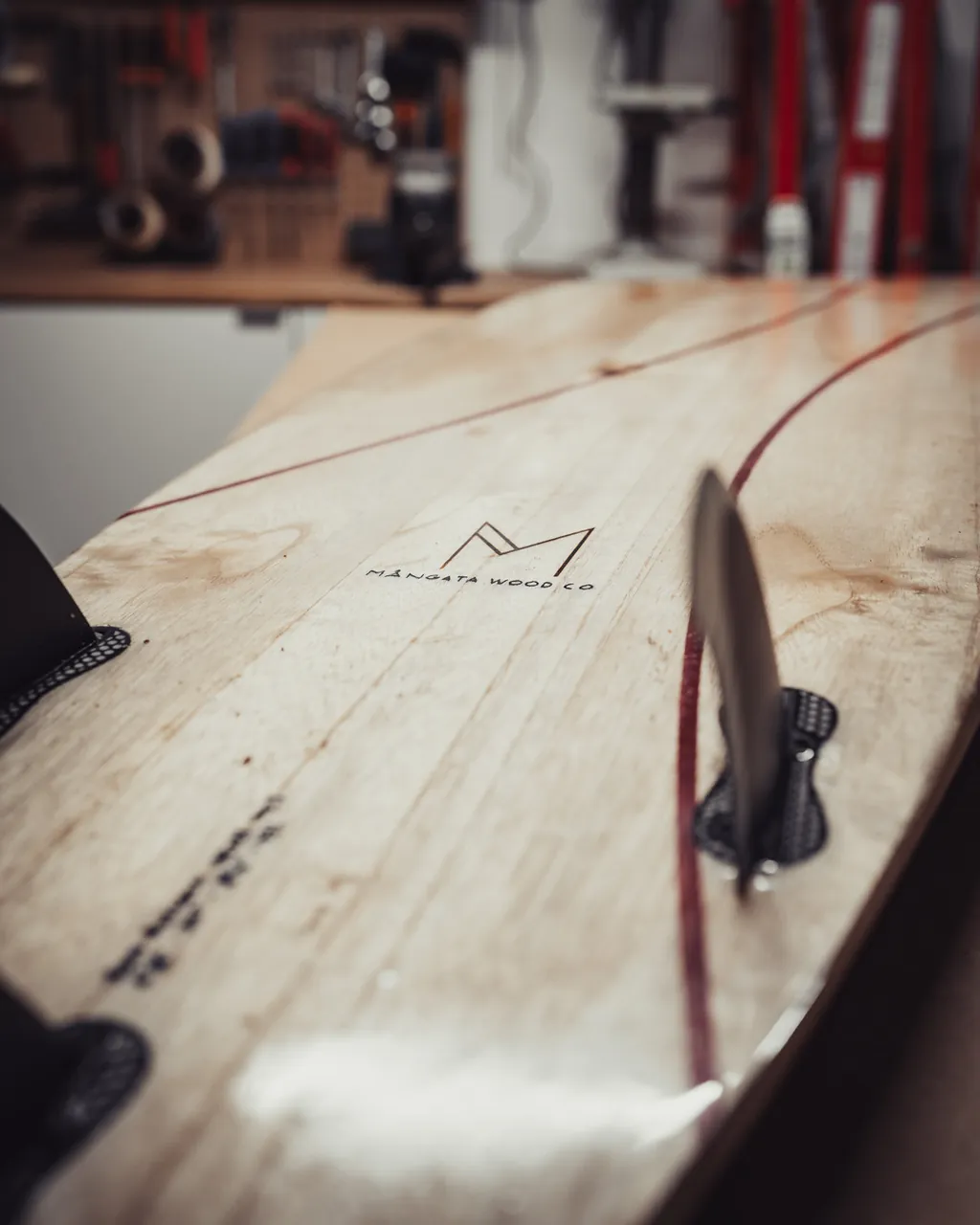 The Mångata mark on the underside of a board, beside a fin and an oxblood inlay line.
